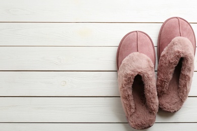 Pair of stylish soft slippers on white wooden background, flat lay. Space for text