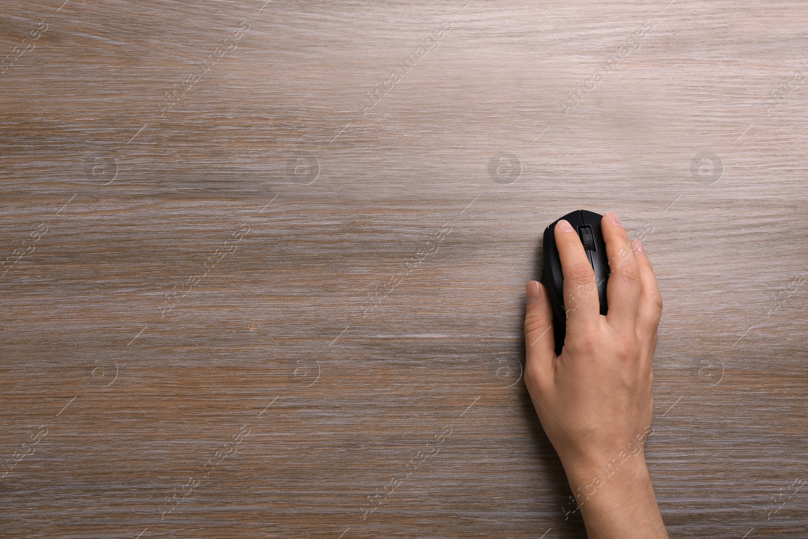 Photo of Woman using computer mouse on wooden table, top view. Space for text