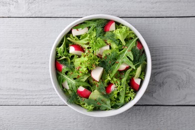 Delicious salad with radish, lettuce and arugula on light gray wooden table, top view