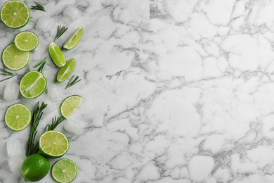 Lemonade layout with juicy lime slices, rosemary and ice cubes on white marble table, top view. Space for text