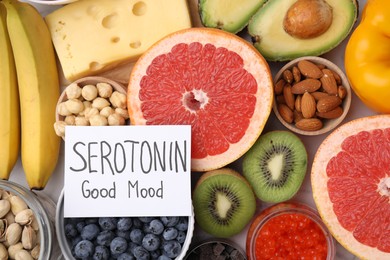 Photo of Many different products and card with phrase Serotonin Good Mood on white table, flat lay. Natural antidepressants