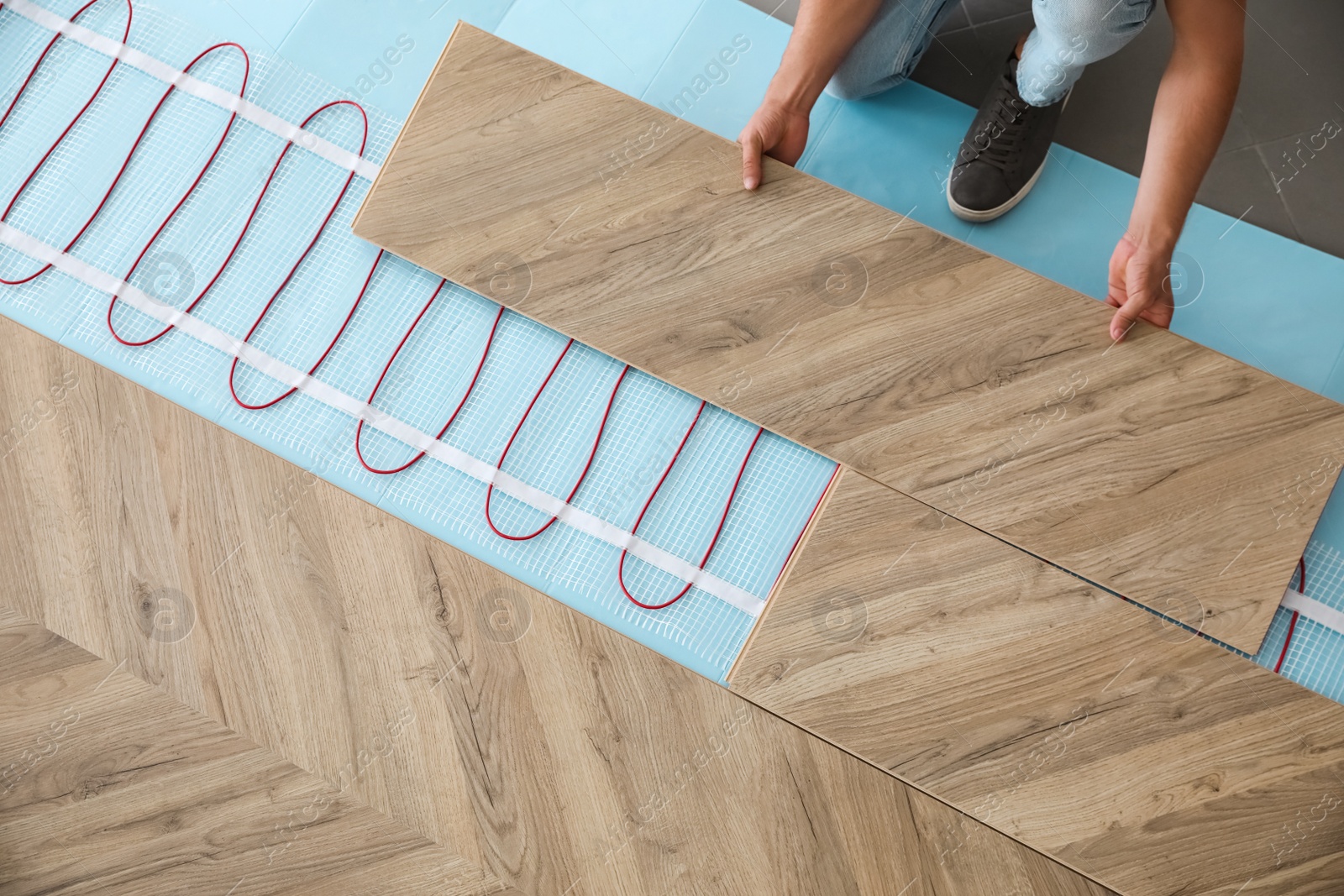 Photo of Professional contractor installing underfloor trace heating system indoors, closeup