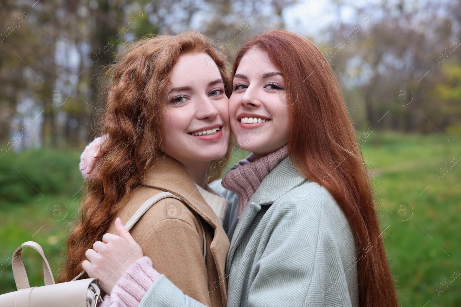 Photo of Portrait of beautiful young redhead sisters in park on autumn day