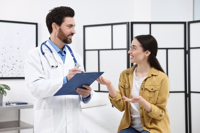 Doctor with clipboard consulting patient during appointment in clinic