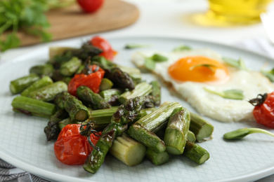 Oven baked asparagus served with fried egg on plate, closeup