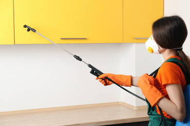 Pest control worker spraying pesticide in kitchen