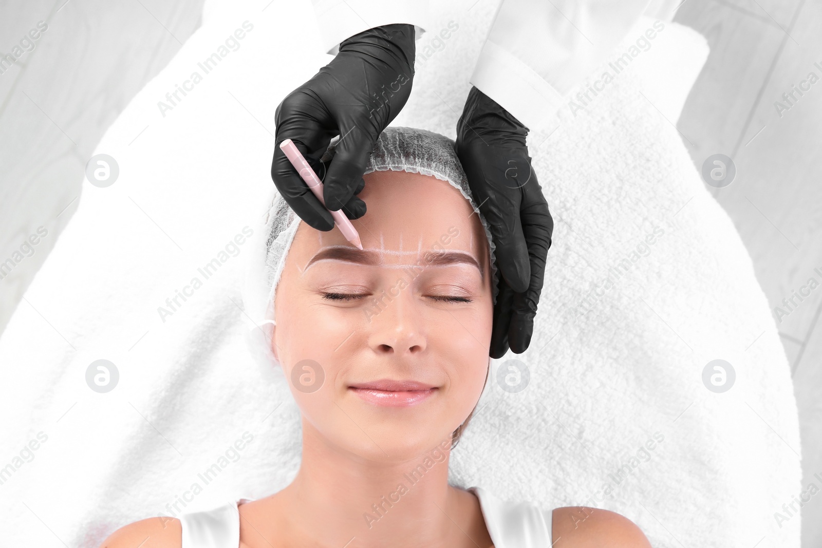 Photo of Young woman undergoing eyebrow correction procedure in salon, top view