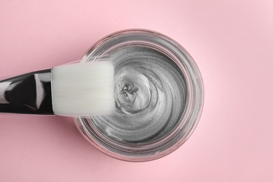 Professional face mask with brush on pink background, top view