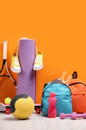 Photo of Many different sports equipment near orange wall indoors