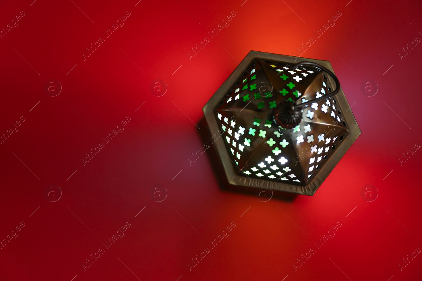 Photo of Decorative Arabic lantern on red background, top view. Space for text