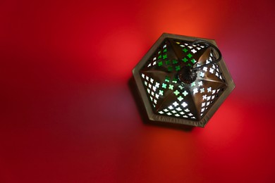 Photo of Decorative Arabic lantern on red background, top view. Space for text