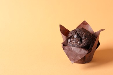 Tasty chocolate muffin on pale orange background, space for text