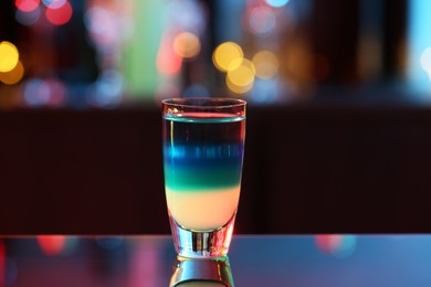Photo of Shooter in shot glass on mirror surface against blurred background
