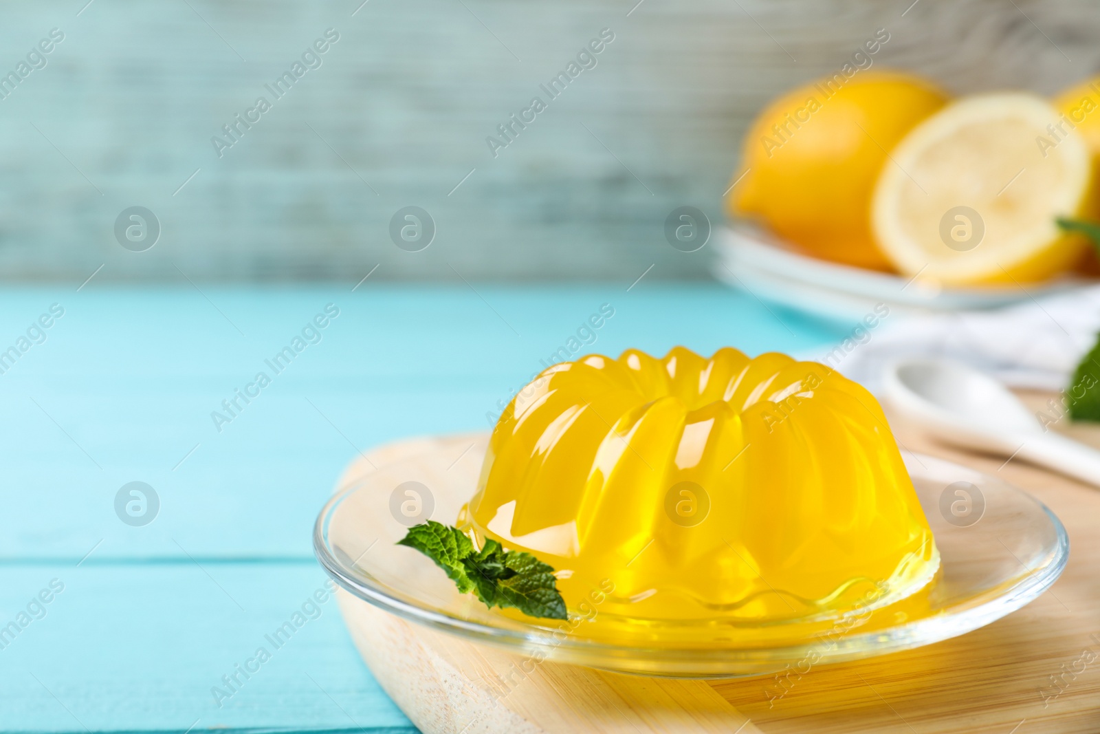 Photo of Delicious yellow jelly with mint on light blue wooden table