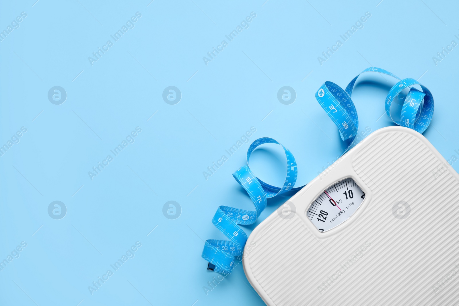 Photo of Scales and measuring tape on light blue background, flat lay. Space for text