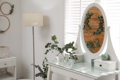 Stylish dressing table decorated with beautiful eucalyptus branches indoors