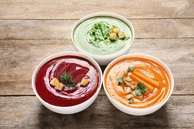 Various cream soups in bowls on wooden table