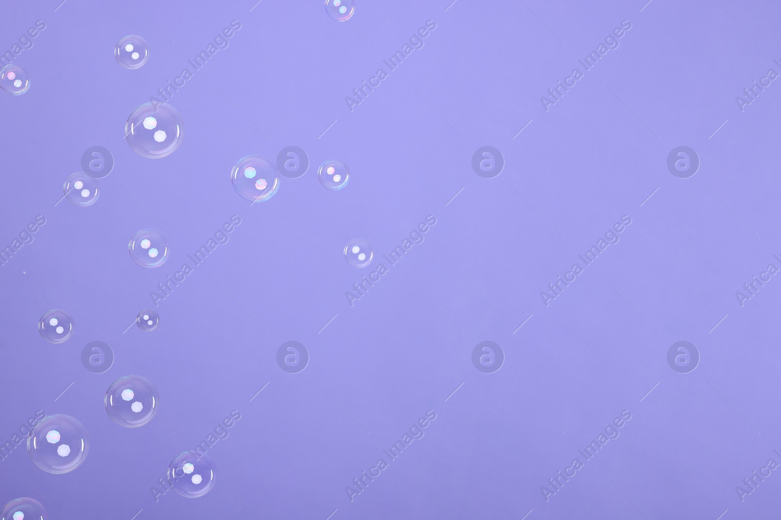 Photo of Many beautiful soap bubbles on violet background. Space for text