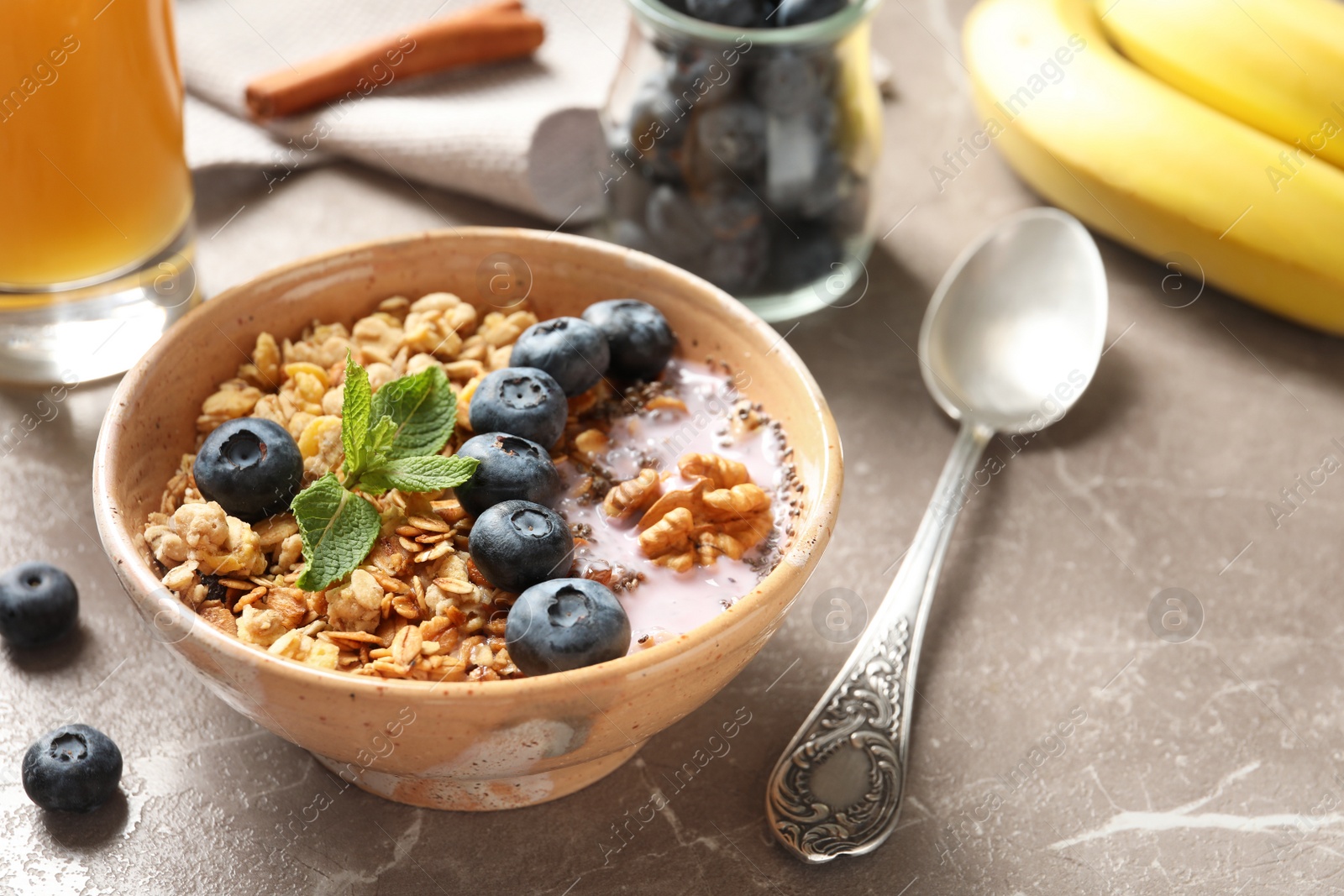 Photo of Bowl of tasty oatmeal with blueberries and yogurt on marble table