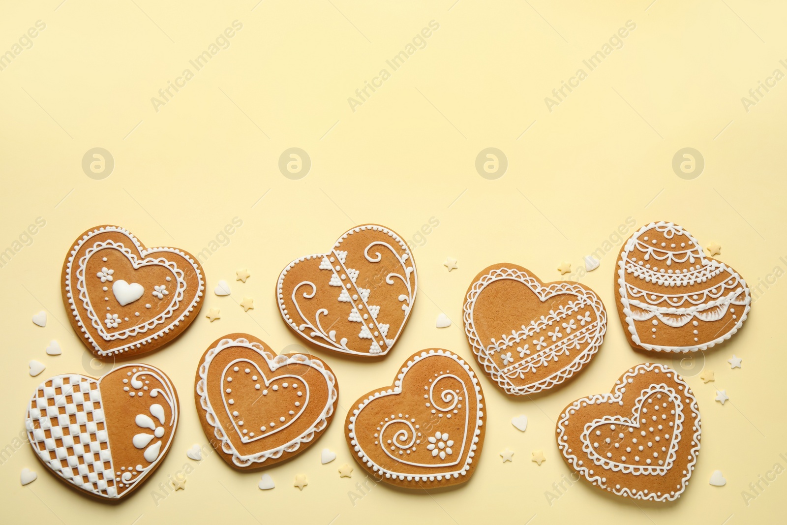 Photo of Tasty heart shaped gingerbread cookies on yellow background, flat lay. Space for text