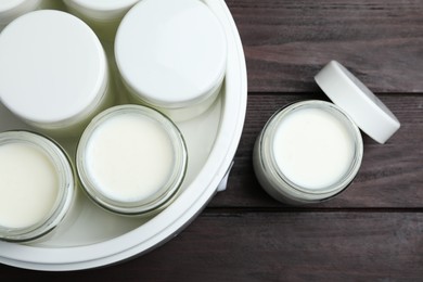 Photo of Modern yogurt maker with full jars on wooden table, flat lay