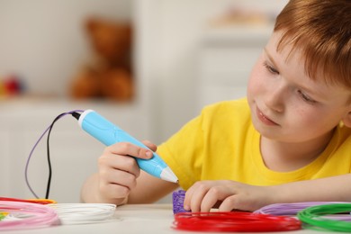 Photo of Boy drawing with stylish 3D pen at white table