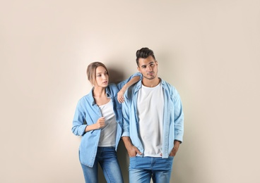 Photo of Young couple in stylish clothes on color background. T-shirts as mockup for design