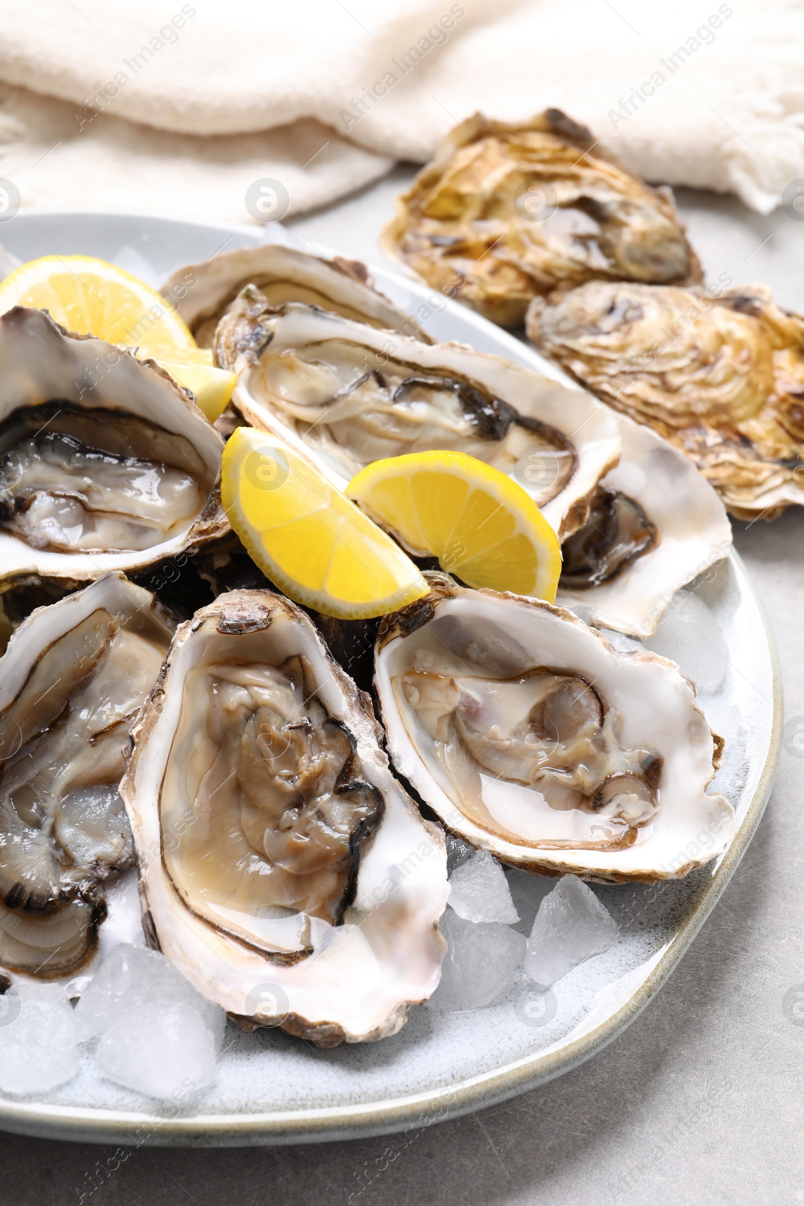 Photo of Fresh oysters with lemon on grey table, closeup