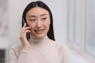 Photo of Portrait of smiling businesswoman talking on smartphone in office
