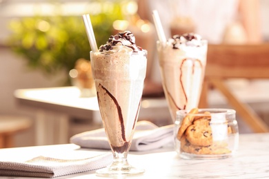 Glass with delicious milk shake on table indoors