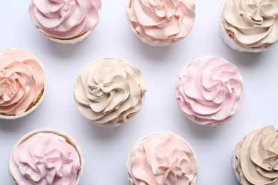 Many tasty cupcakes on white background, flat lay