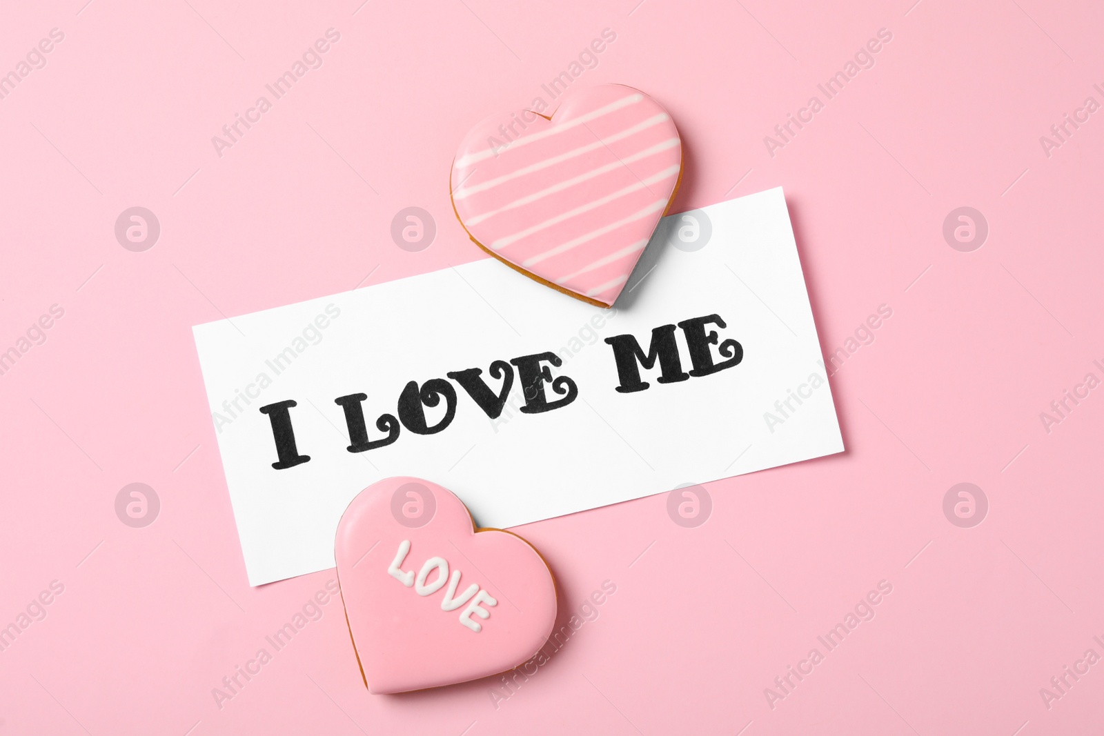 Photo of Paper with handwritten phrase I Love Me and heart shaped cookies on pink background, flat lay