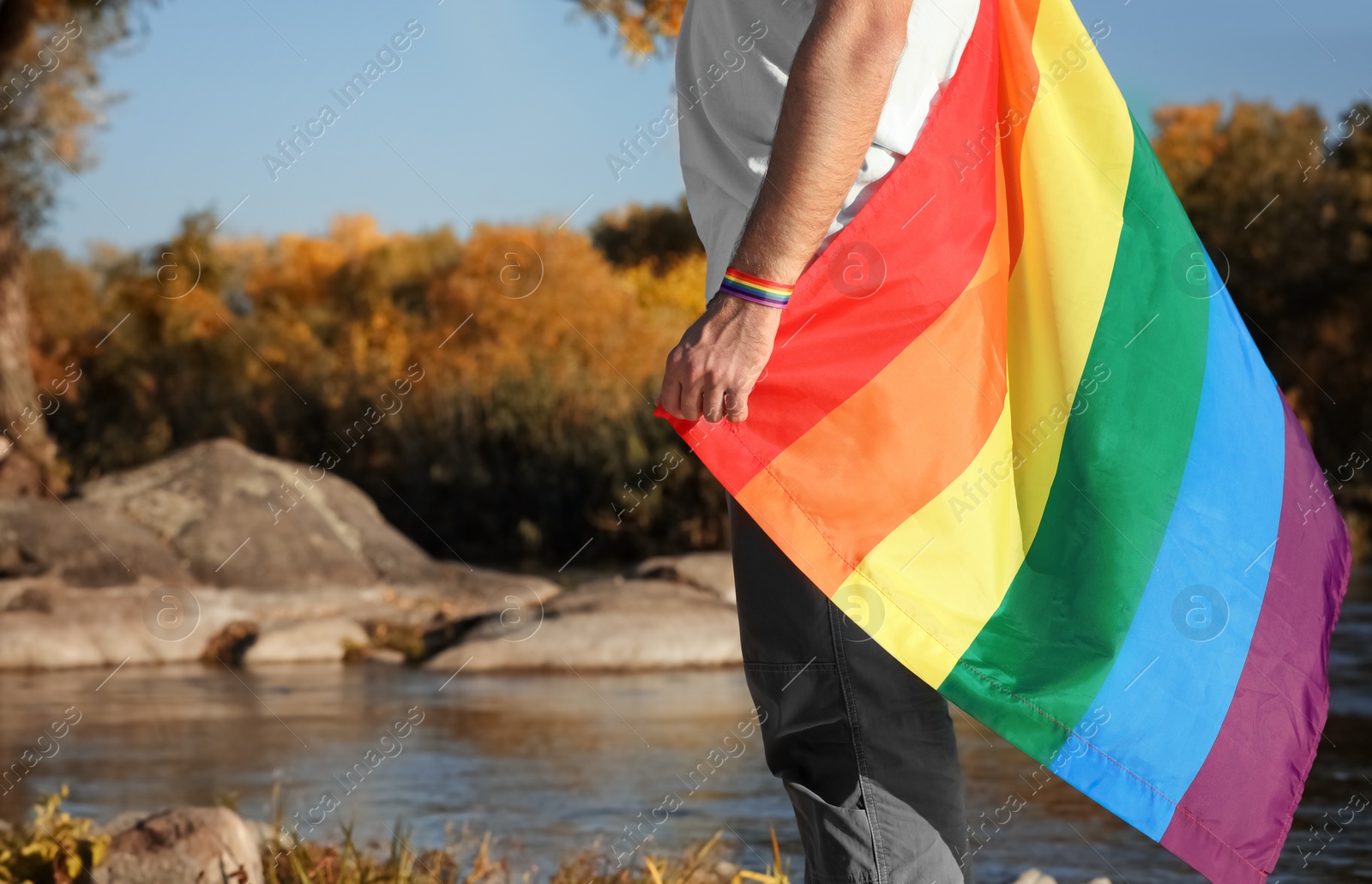 Photo of Man with rainbow LGBT flag outdoors, space for text. Gay symbol