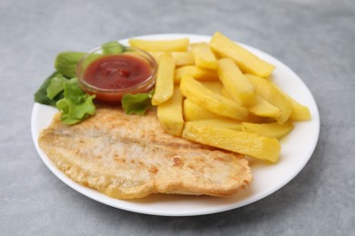 Photo of Delicious fish and chips with ketchup and lettuce on gray table, closeup