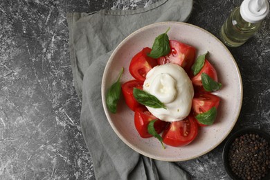 Photo of Delicious burrata cheese with tomatoes and basil, oil and peppercorns on grey table, flat lay. Space for text
