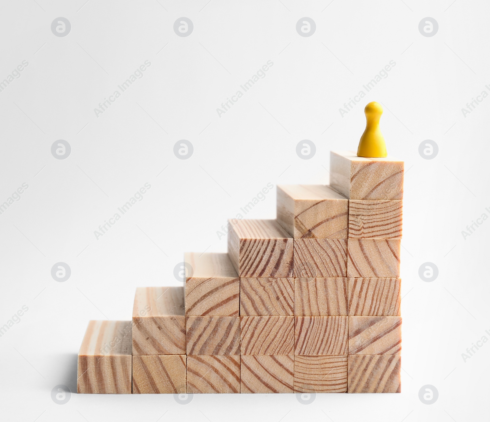 Photo of Yellow game piece on top of stairs against white background. Career promotion concept