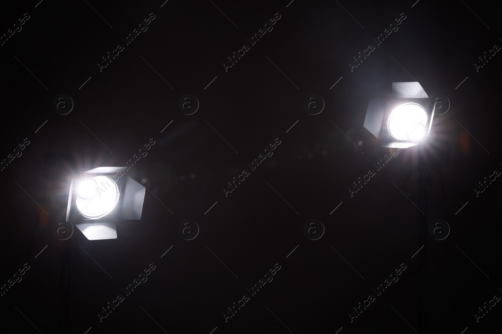 Photo of Bright white spotlights in darkness, space for text