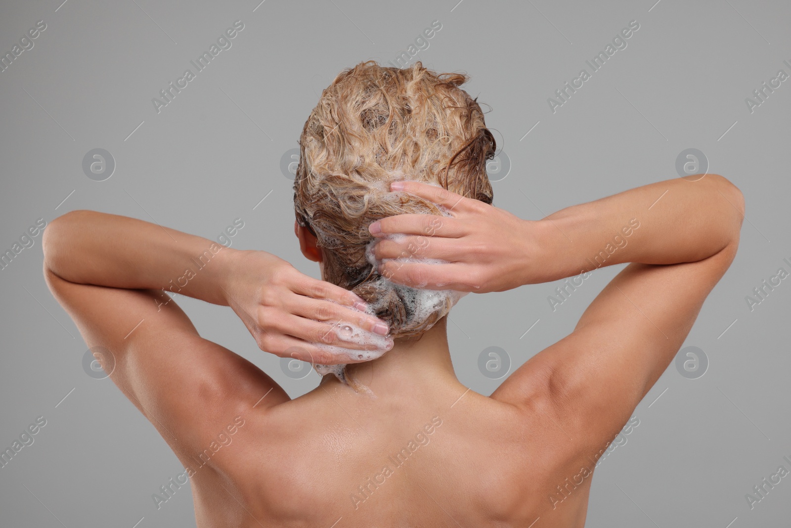 Photo of Woman washing hair on light grey background, back view