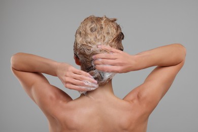 Woman washing hair on light grey background, back view