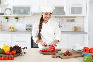 Professional chef cutting pepper on table in kitchen