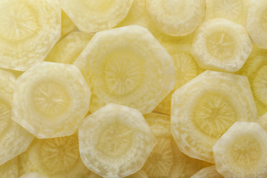 Pieces of raw white carrot as background, top view