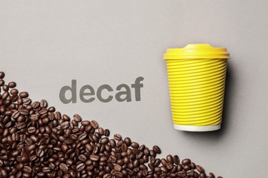 Photo of Word Decaf, coffee beans and takeaway paper cup on light grey background, flat lay
