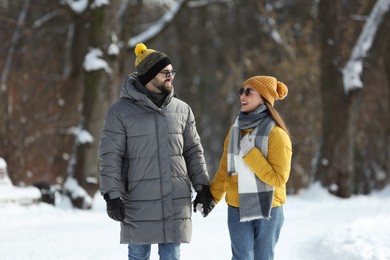 Photo of Happy young couple walking in snowy park on winter day