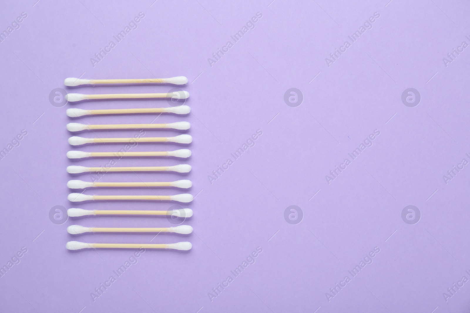 Photo of Wooden cotton buds on violet background, flat lay. Space for text