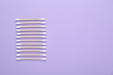 Photo of Wooden cotton buds on violet background, flat lay. Space for text