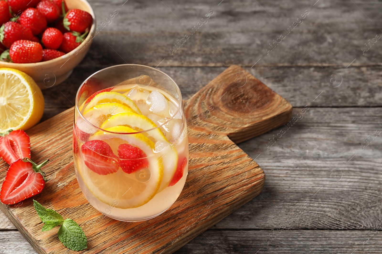 Photo of Natural lemonade with strawberries in glass on table