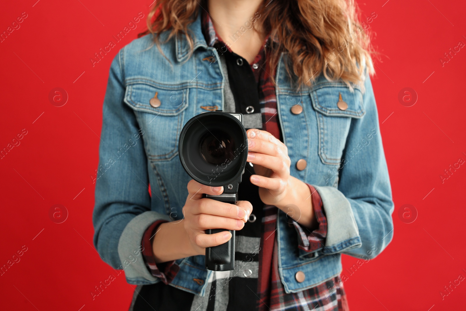 Photo of Woman with vintage video camera on red background, closeup