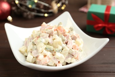 Photo of Traditional russian salad Olivier served on wooden table, closeup