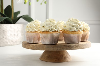 Tasty vanilla cupcakes with cream on white wooden table