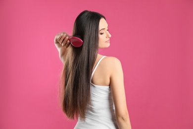 Photo of Beautiful young woman with hair brush on color background